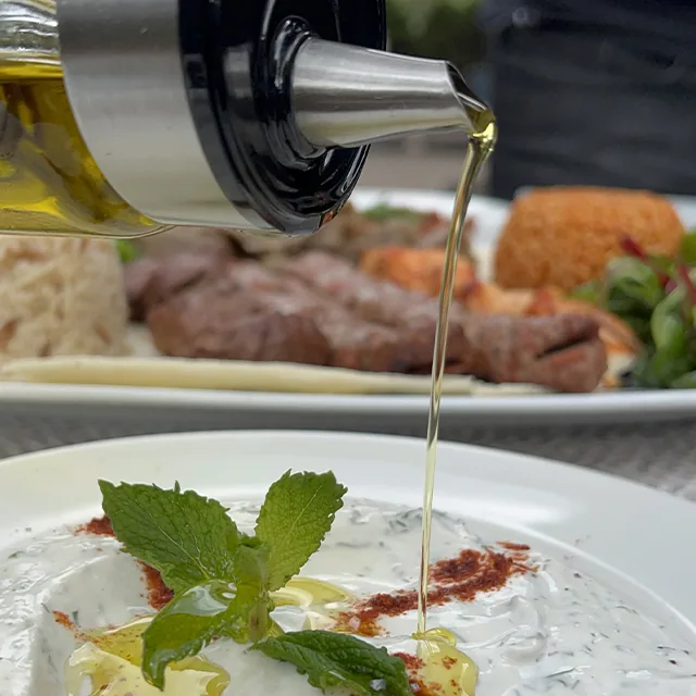 Olive oil poured over cacık with fresh mint