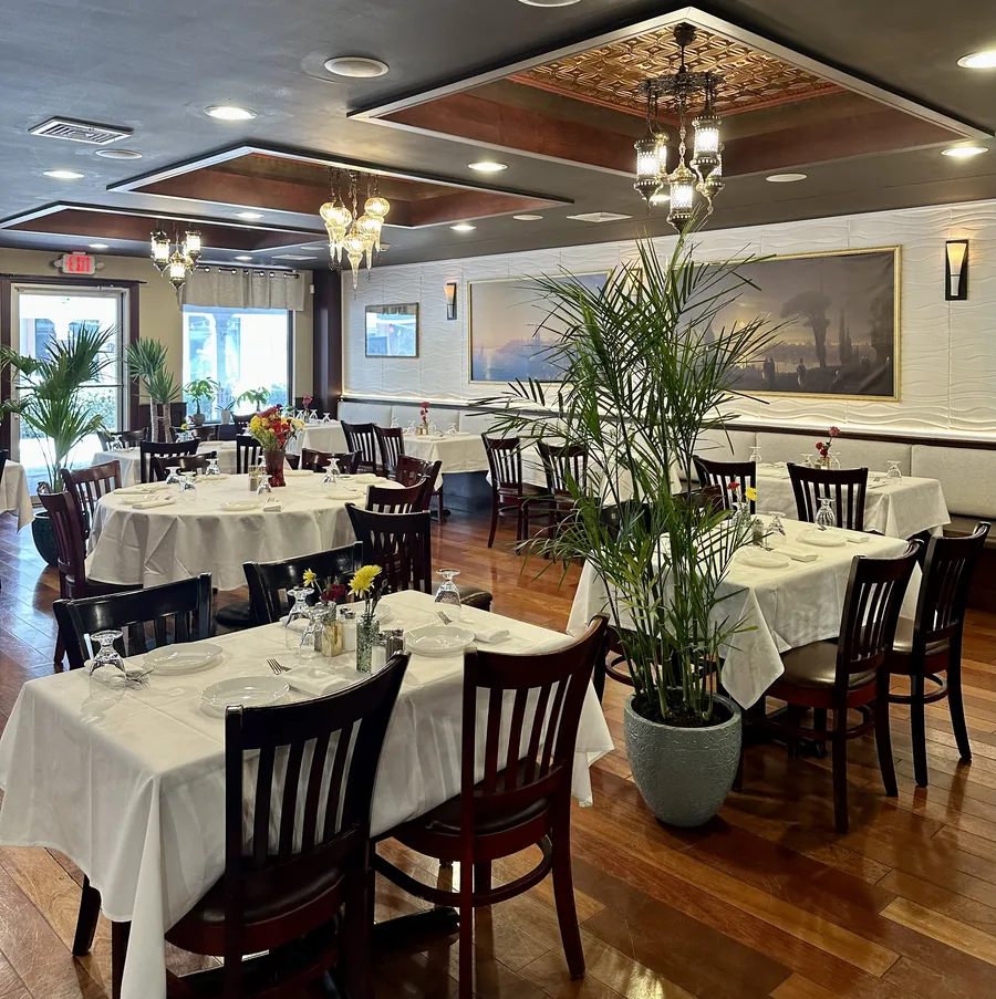 The dining room at Zaytin: white tablecloths, mosaic lamps, and the Istanbul painting